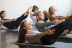 A group of men and women performing core exercise in Pilates class.