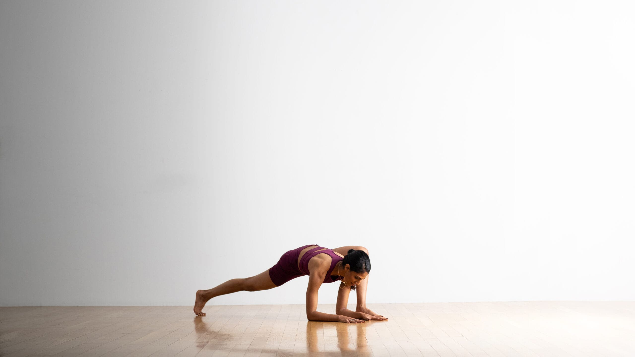 Neeti Narula practices a variation of a Forearm Plank with one leg forward in a lunge position.