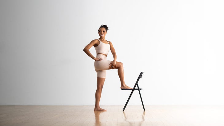 Patrice Grahamm practices a standing twist with one foot on the seat of a chair.