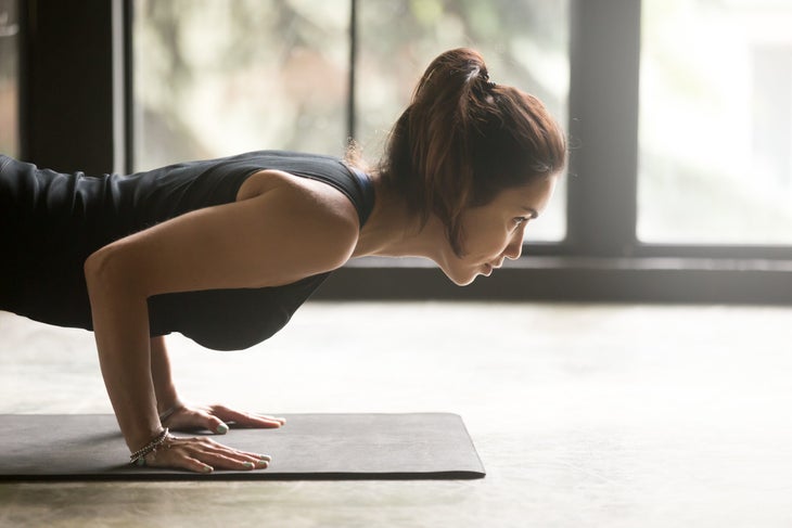 Woman does Four-Limbed Staff Pose while practicing Surya Namaskar A