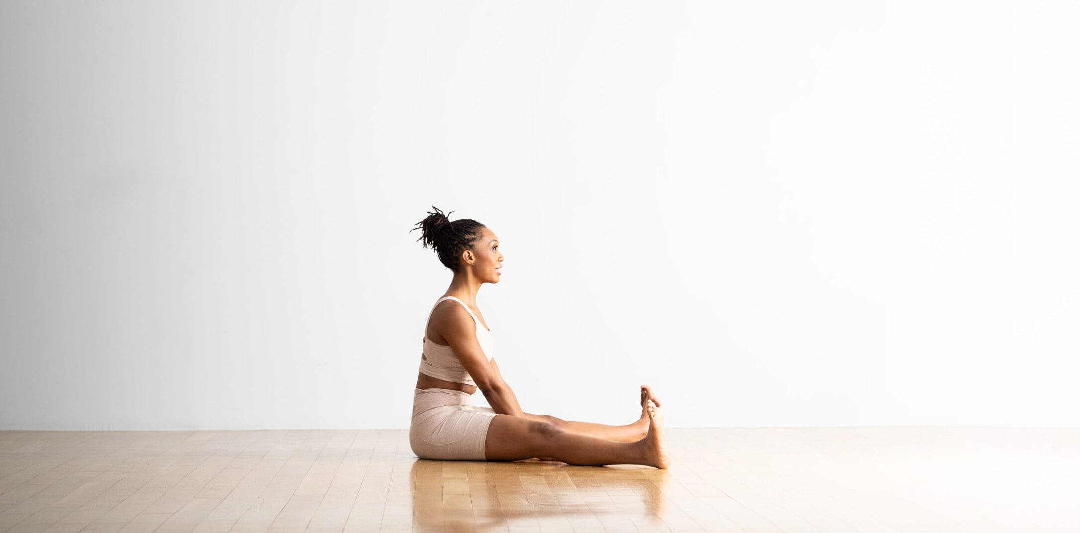 A woman practices Wide Angle Seated Forward Bend.