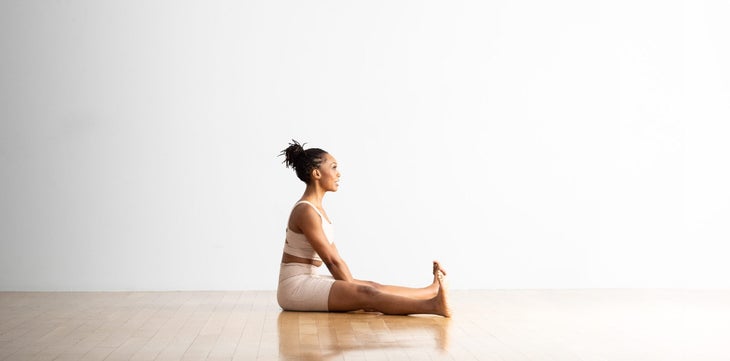 A woman practices Wide Angle Seated Forward Bend.