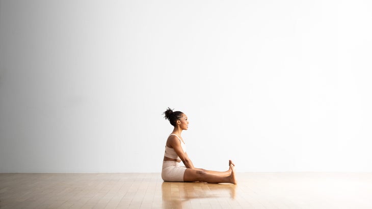 A woman practices Wide Angle Seated Forward Bend. 