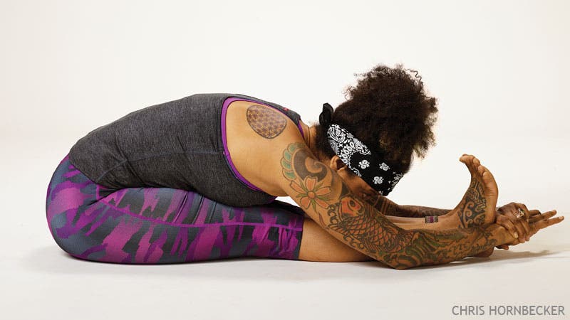 A woman practices Paschimottanasana (Seated Forward Bend) in yoga