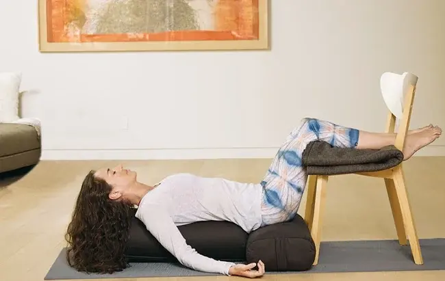 Woman performing legs on a chair pose on her yoga mat.