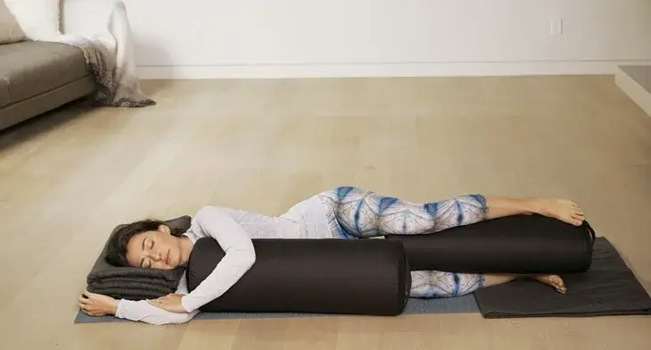 Woman performing side lying corpse pose on her yoga mat.