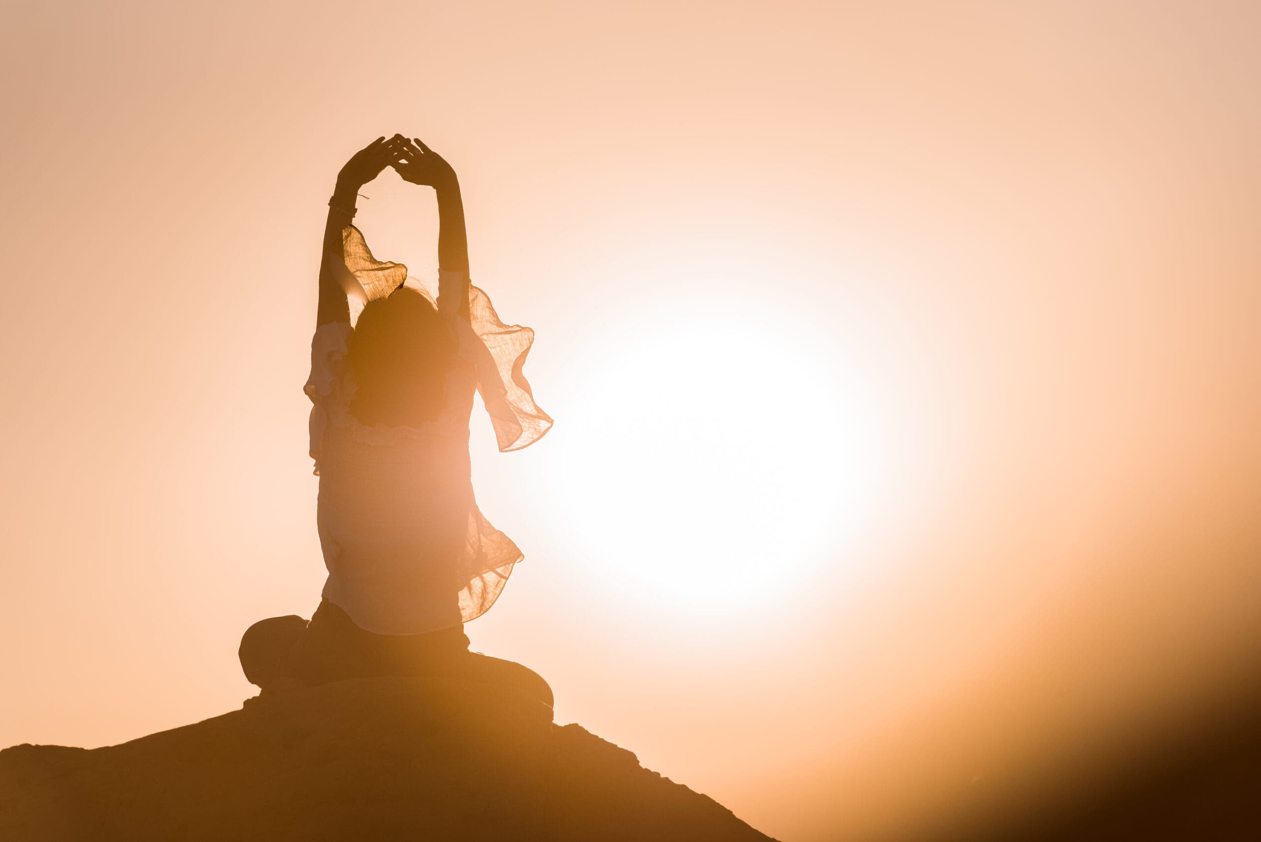 Women meditating with arms stretched overhead, root chakra