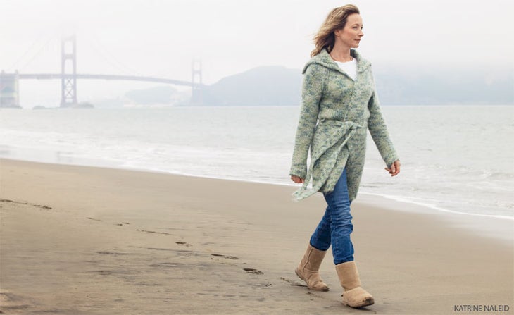 older woman walking on beach golden bay bridge