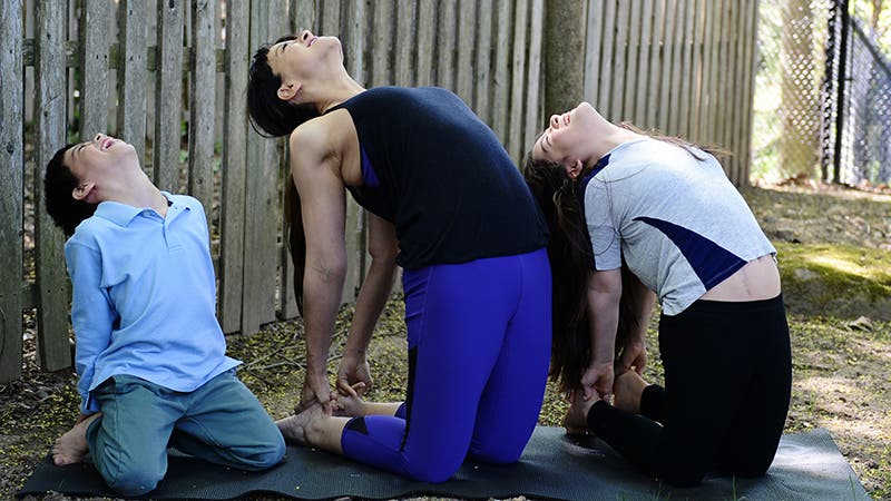 Masumi Goldman doing Camel Pose with her kids.