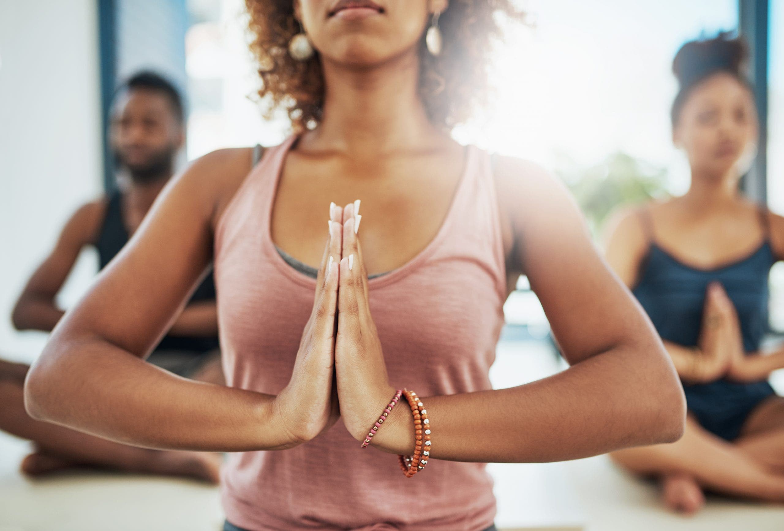 Group of people doing yoga with hands in anjali mudra