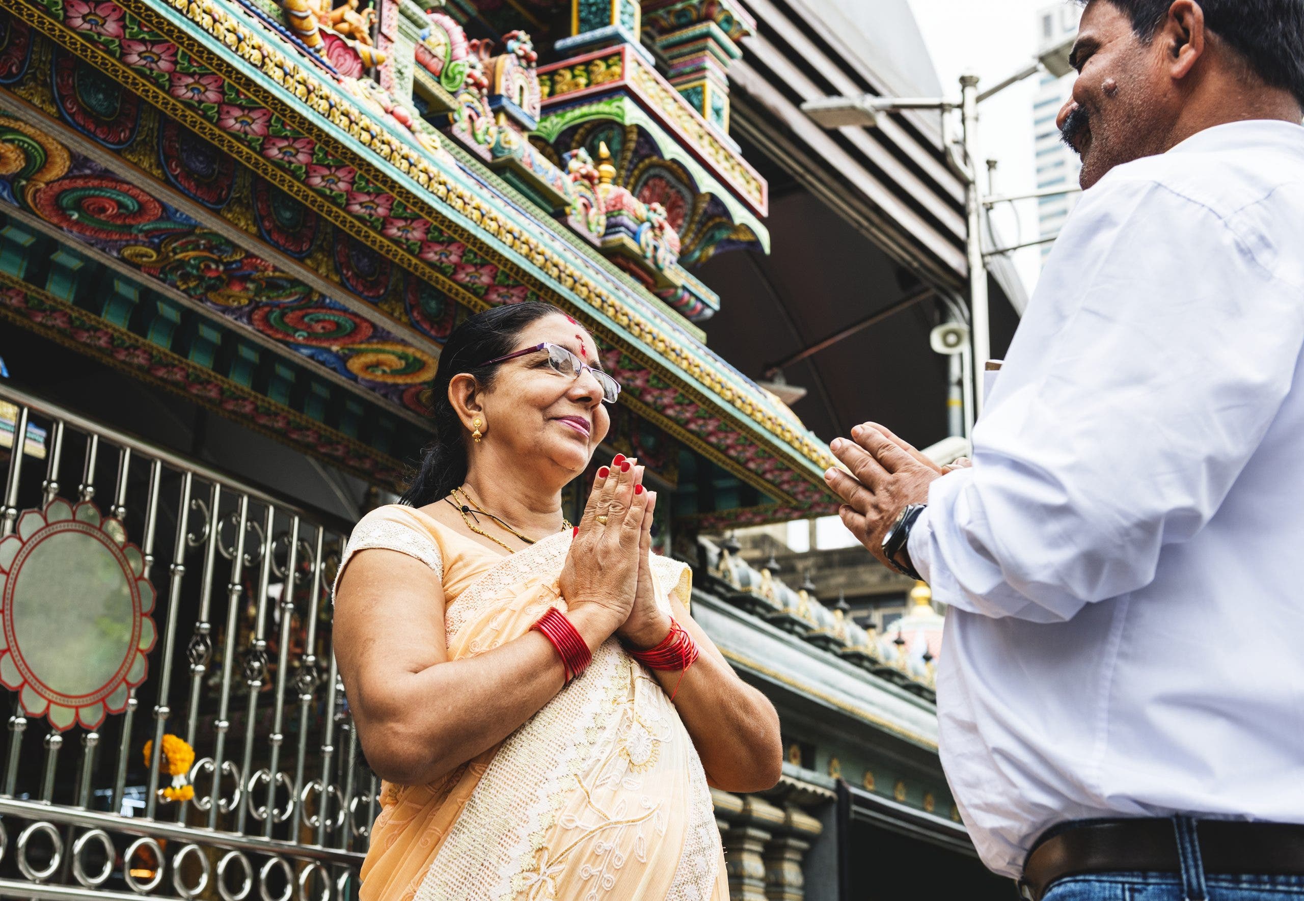 Indian couple namaste greeting with anjali mudra under colorful awning