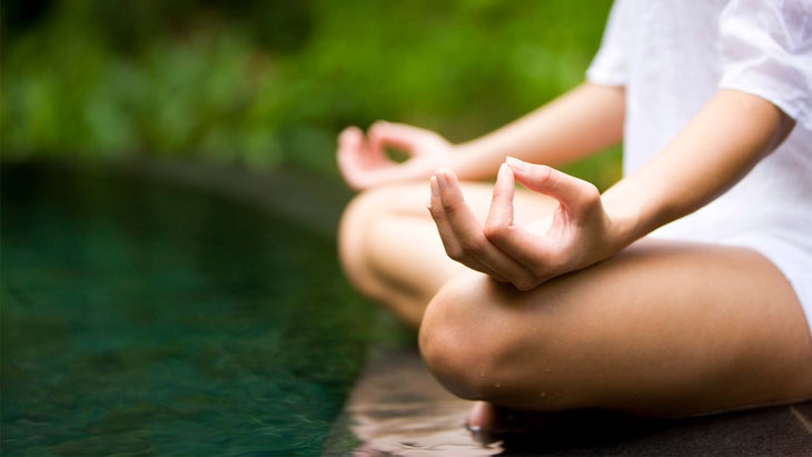 A person meditates with their hands in a gyana mudra 