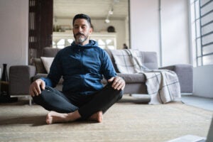 Man meditating in his living room.