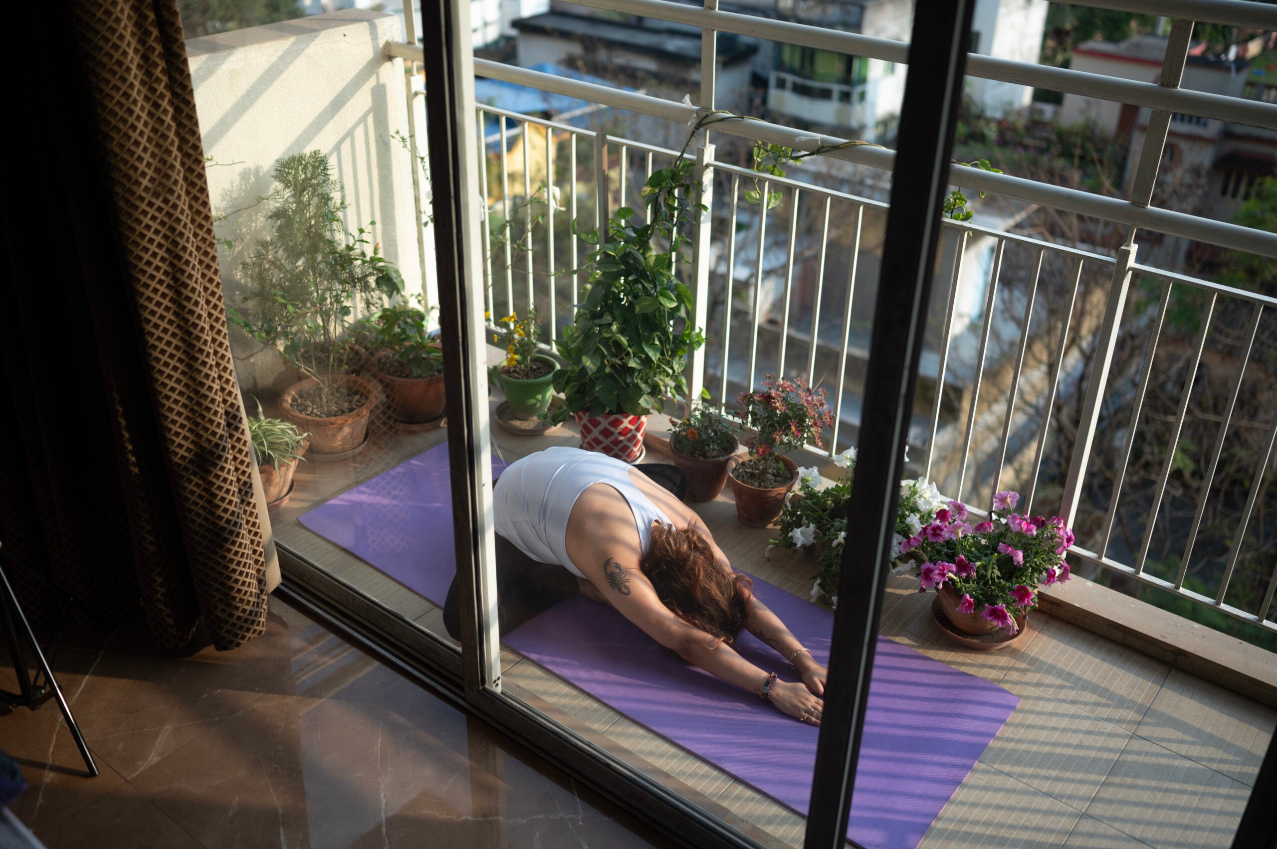Image woman on an apartment balcony doing a butterfly stretch.