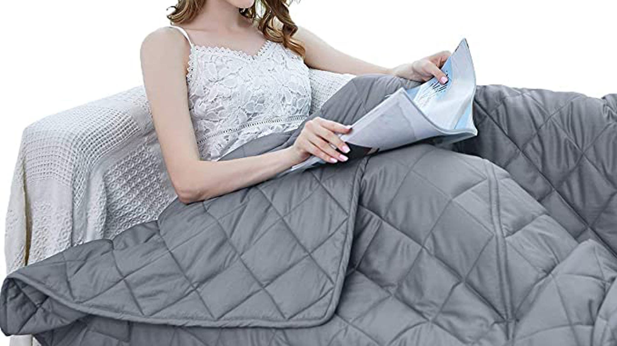 Woman reading under gray quilted weighted blanket
