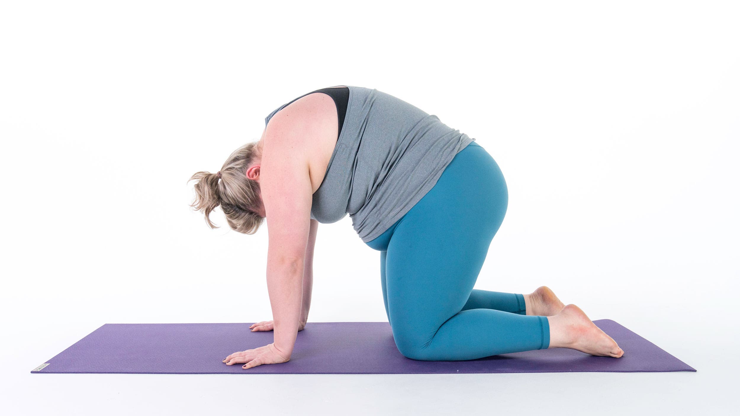 A woman demonstrates Marjaryasana (Cat Pose) to stretch shoulder muscles in yoga