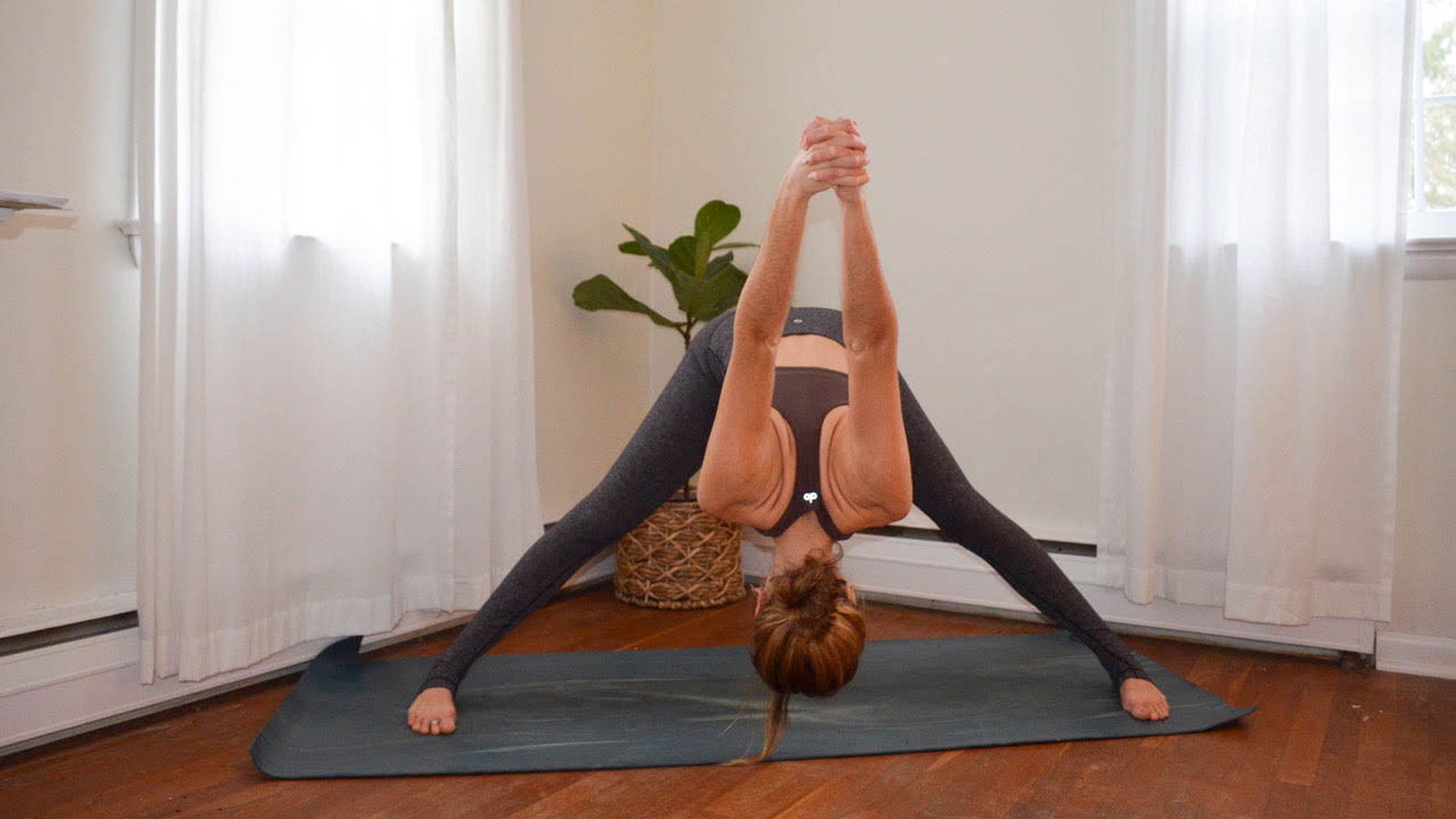 A woman performs Prasarita Padottanasana (Wide-Legged Standing Forward Bend) in yoga