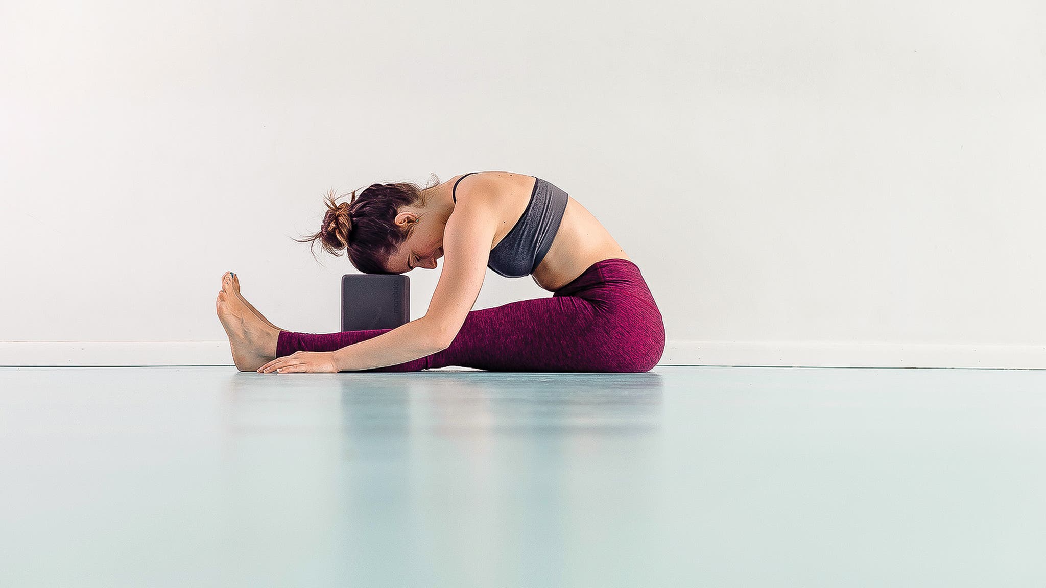 Woman demonstrating Paschimottanasana Variation, Seated Forward Bend
