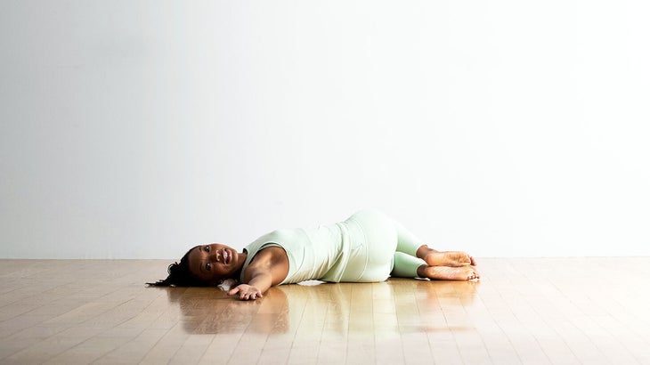 A woman demonstrates twisting the spine in a lying position during yoga