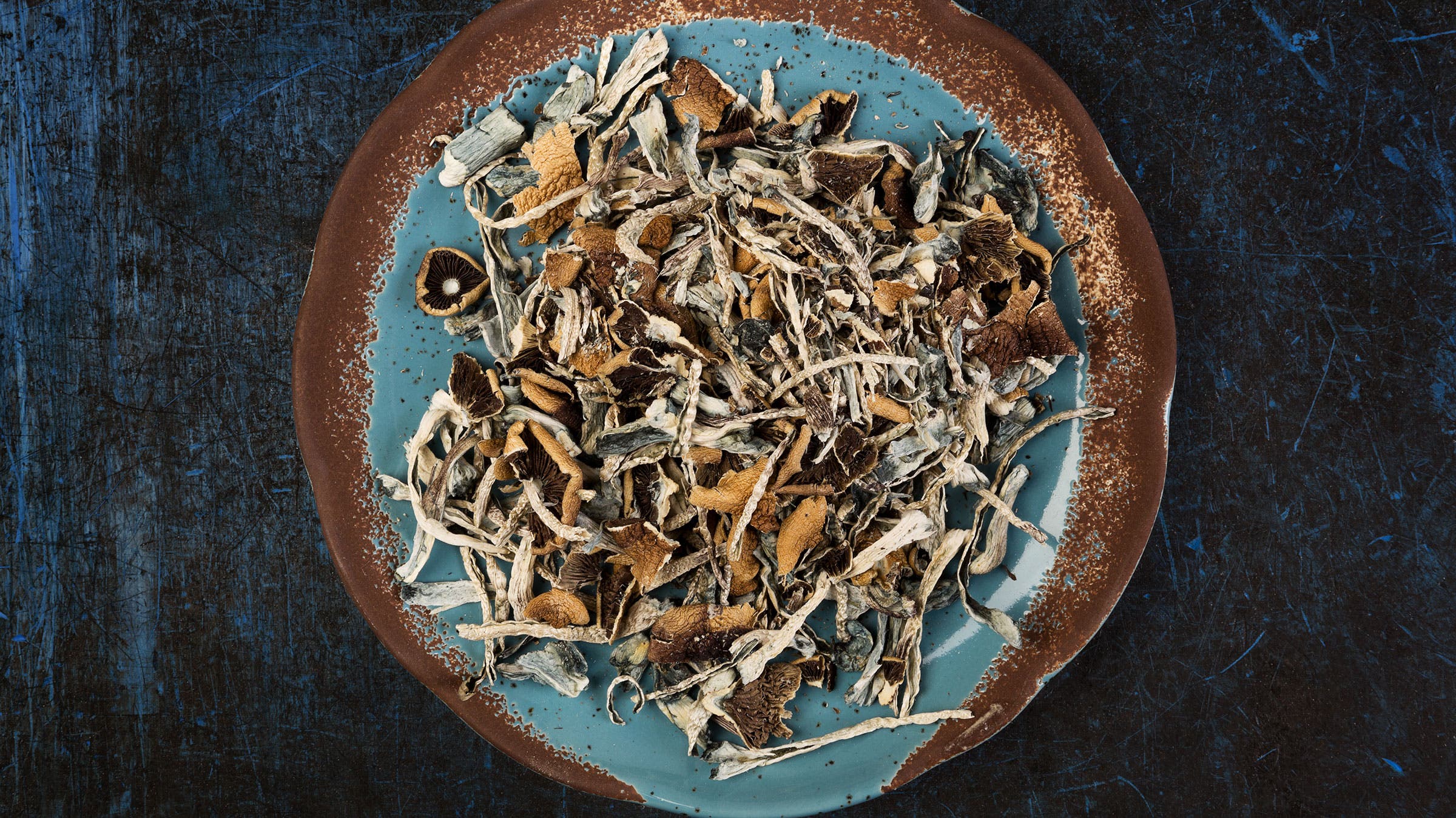 A plate of psilocybin "magic" mushrooms is shown on a black background