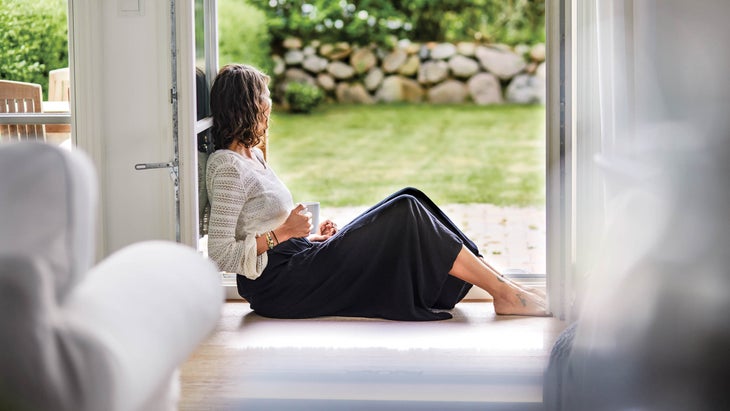 Young woman sitting in window frame looking out