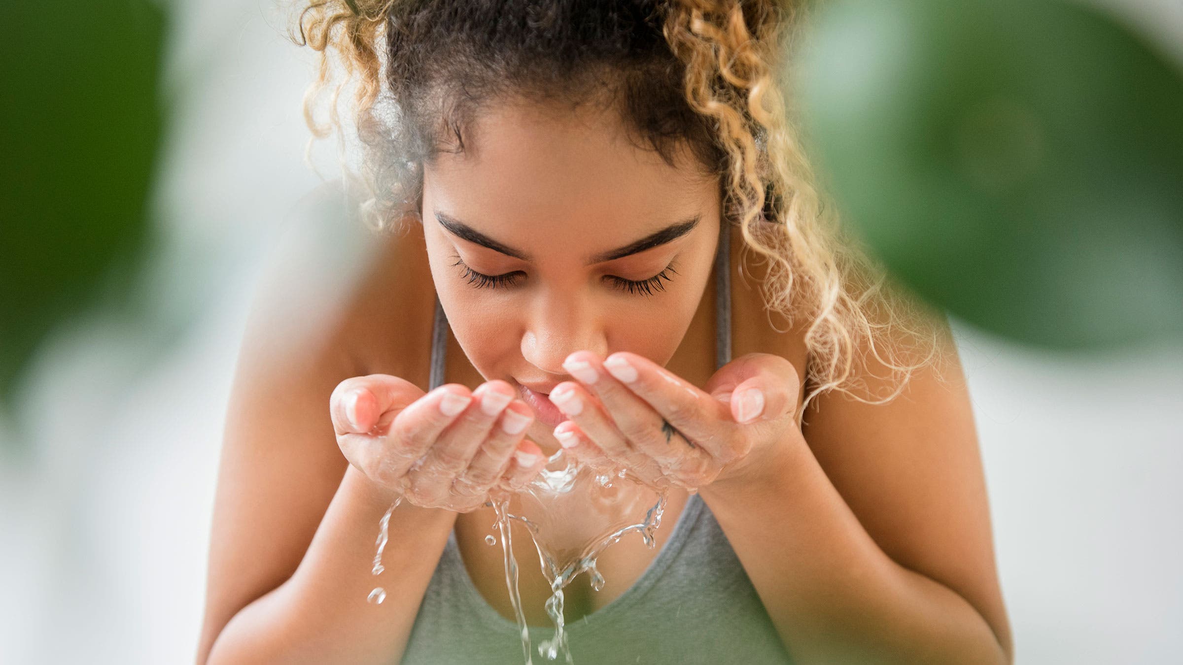 A woman washes her face with water