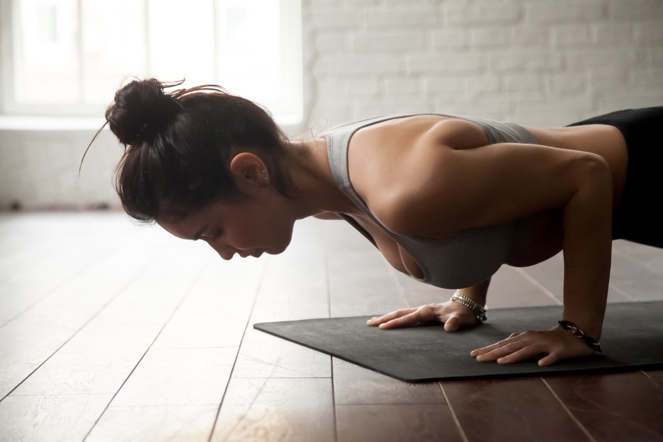 Young woman practicing yoga, standing in chaturanga dandasana exercise, four limbed staff pose