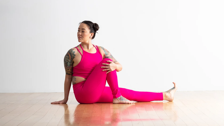 Woman performing marichyasana in pink workout outfit.