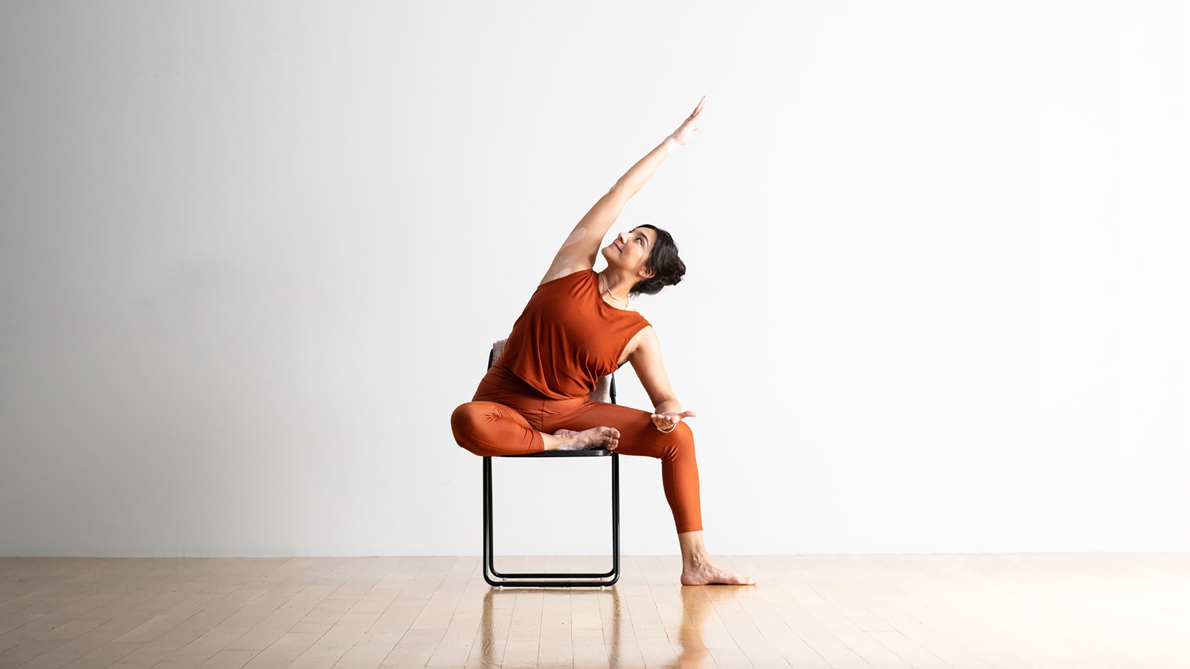 Woman demonstrating Revolved Head-to-Knee Pose in a chair