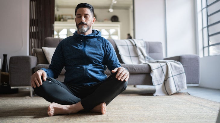 Man sits and meditates in his house