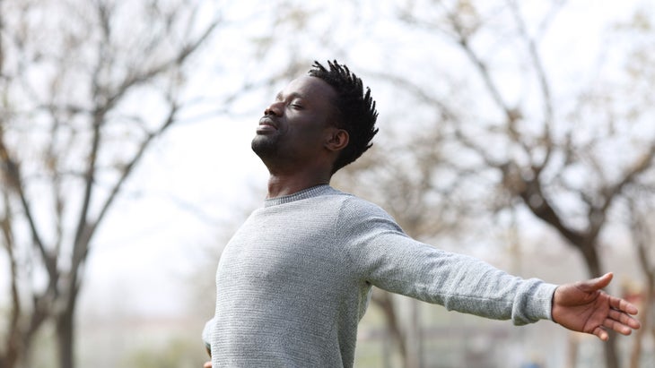 Man stands with his eyes closed and arms outstretched