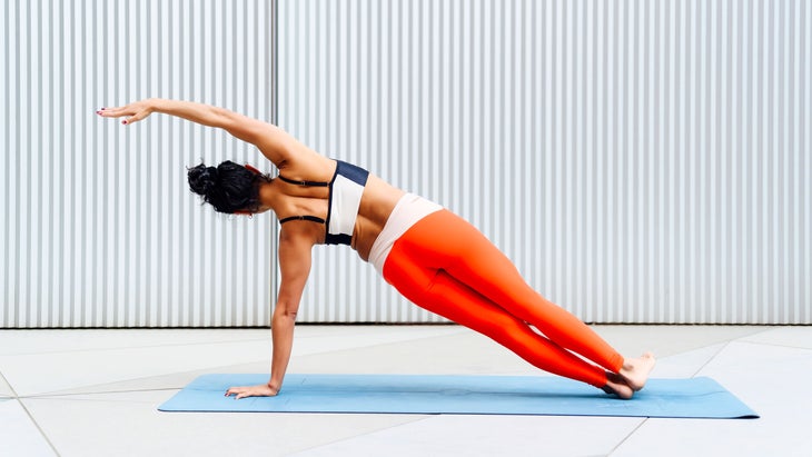 Woman practices yoga poses for strength as she does a side plank