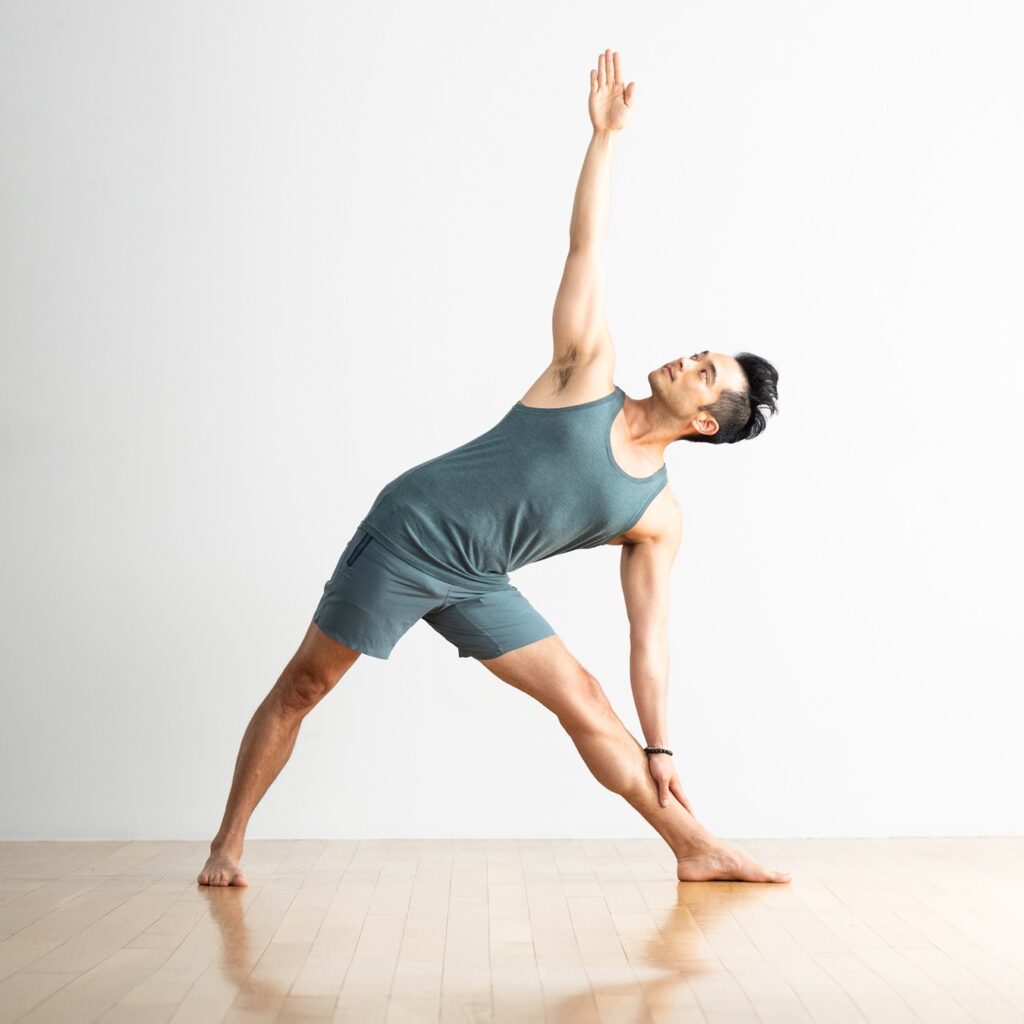 Sporty young man practicing yoga, doing stretching exercise, extended triangle  pose, utthita trikonasana asana for flexible Stock Photo - Alamy