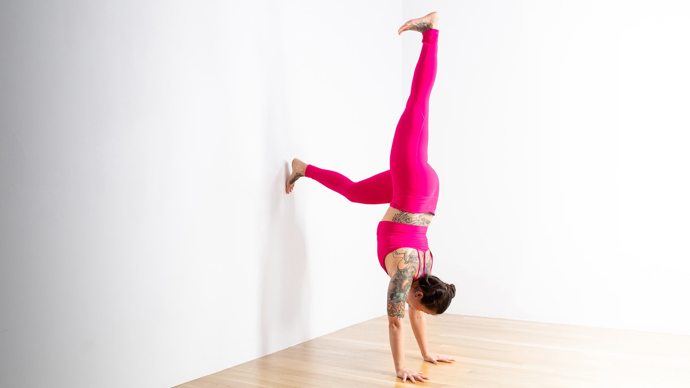 Woman in a Handstand modification against a wall