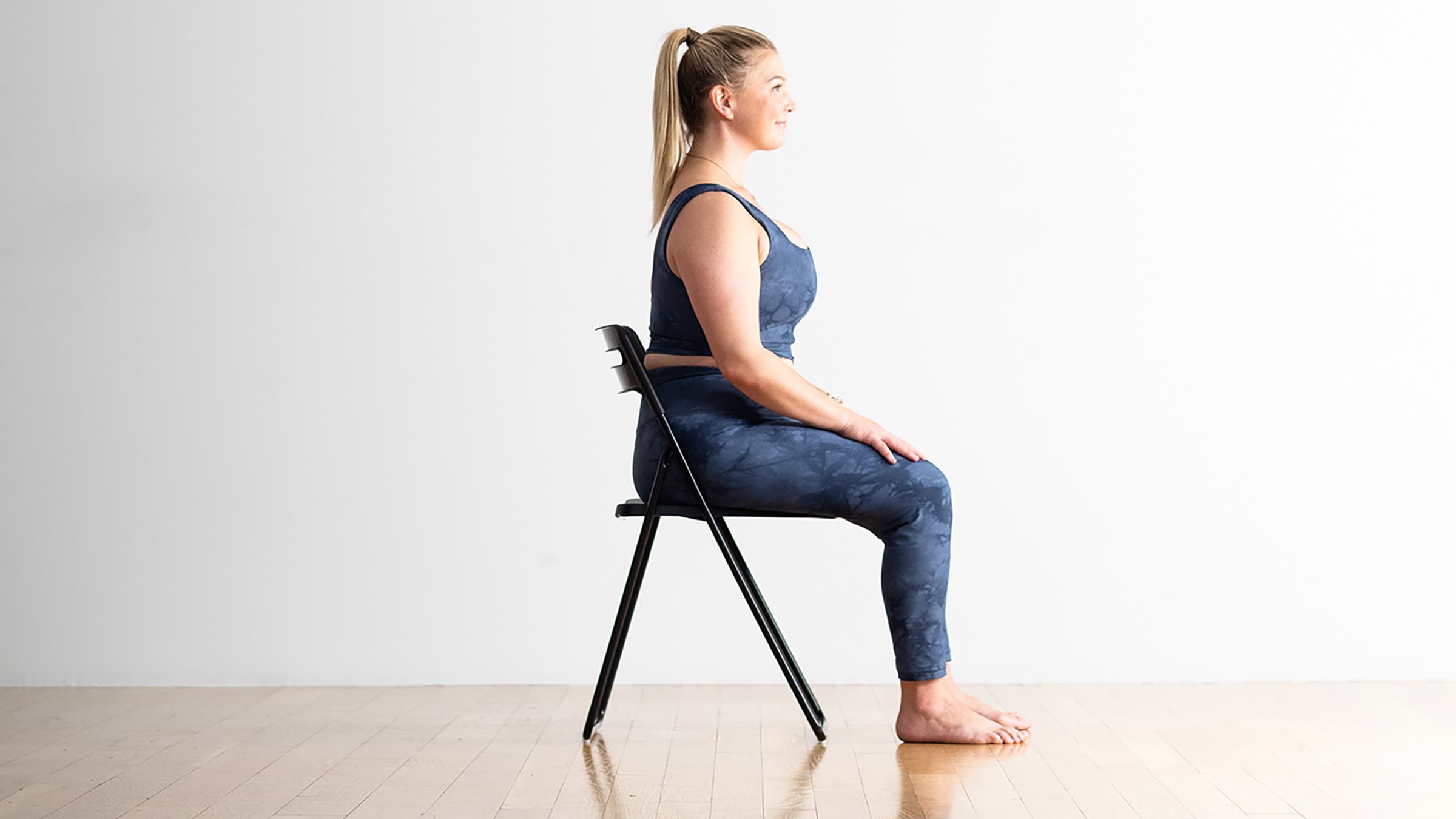 Woman demonstrating Lotus Pose in a chair