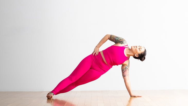 A person demonstrates a variation of Side Plank in yoga, with scissor step