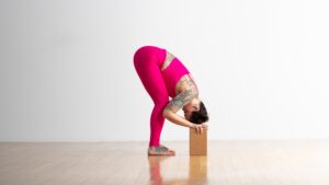 Woman doing forward bend with hands on blocks.