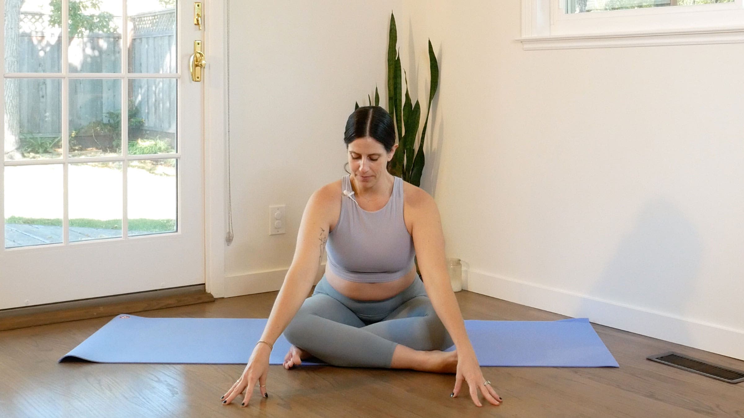 Woman sitting on her yoga mat, cross-legged and leaning forward, while practicing a 15-minute yoga flow