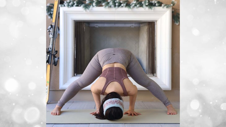 Ingrid Yang in wide leg forward fold in front of a fireplace