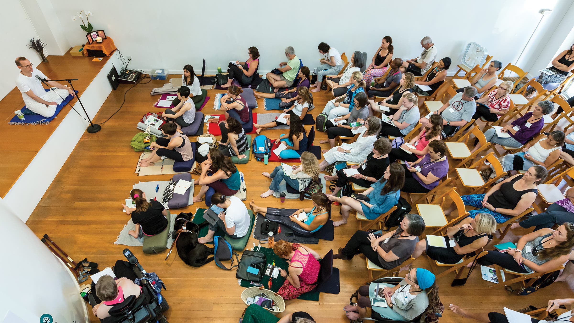 Jivana Heyman on stage in front of people sitting on chairs or yoga mats