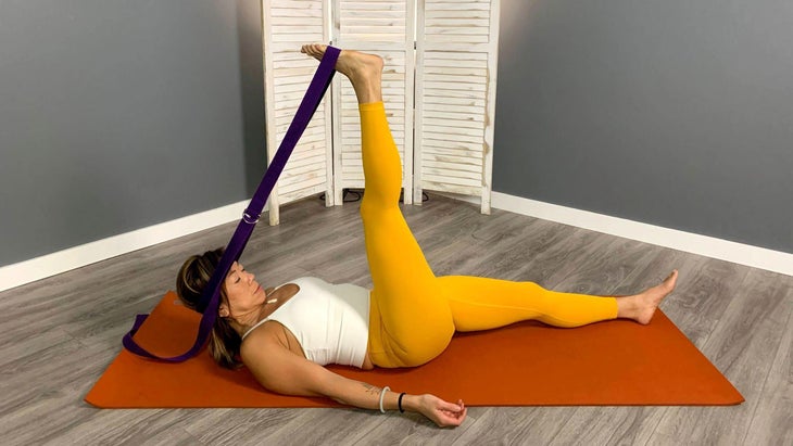 Lisa Jang practices Hammock Pose with a strap