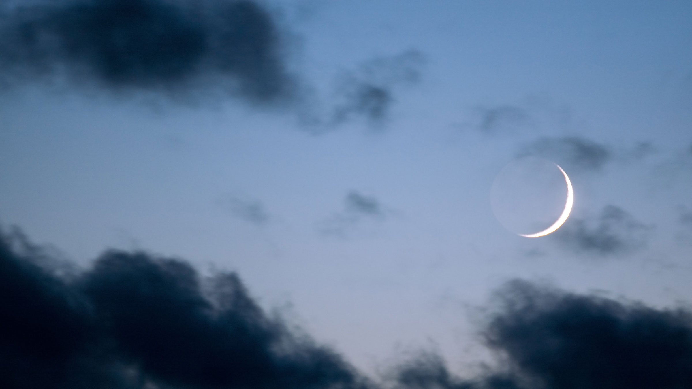 A sliver of a new Moon is pictured in a night sky