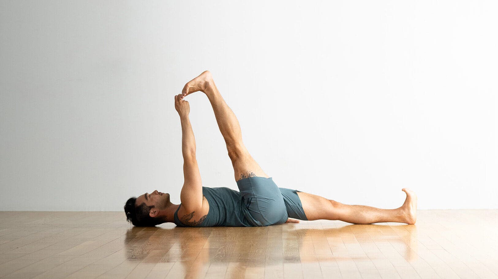 A person demonstrates Supta Padangusthasana I (Reclining Hand-to-Big-Toe Pose I) in yoga