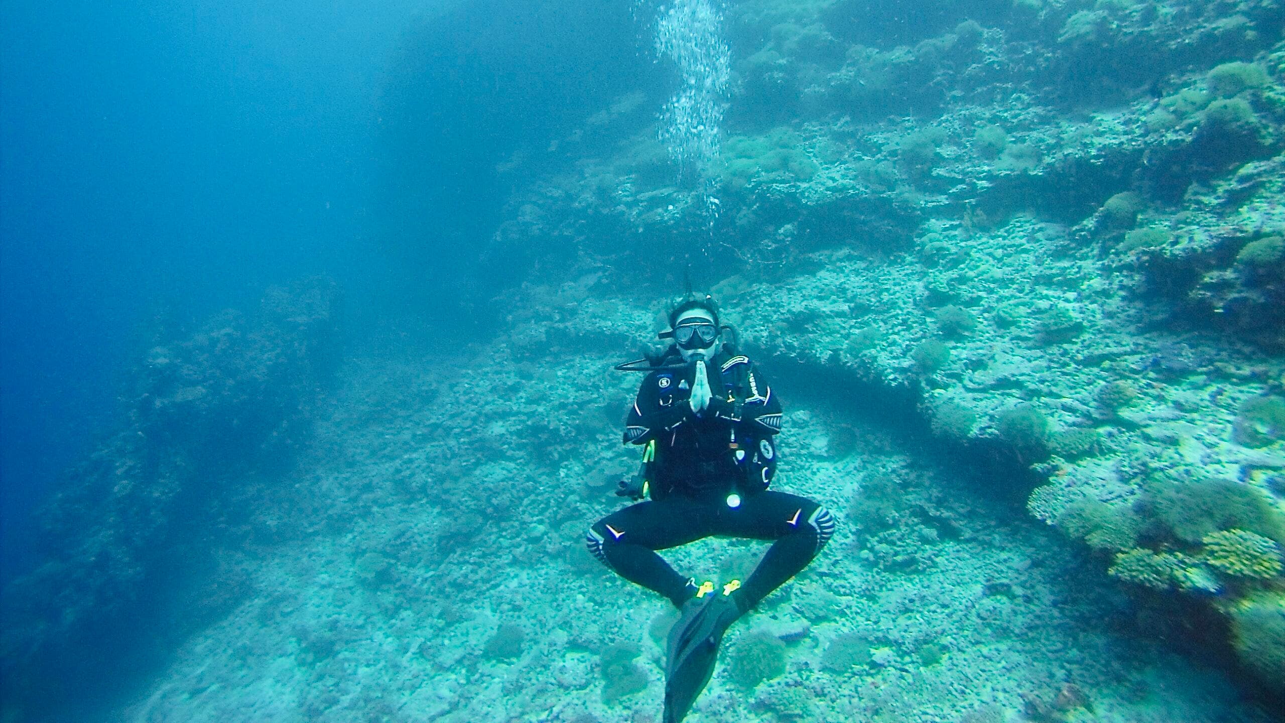 Person in scuba gear practices Baddha Konasana while diving in the ocean