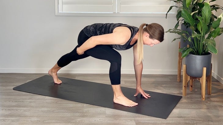 A person practices a Low Lunge in yoga with her hand on her glute