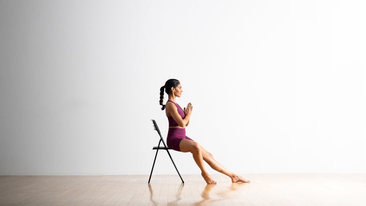 South Asian woman practices Bound Angle pose in a chair