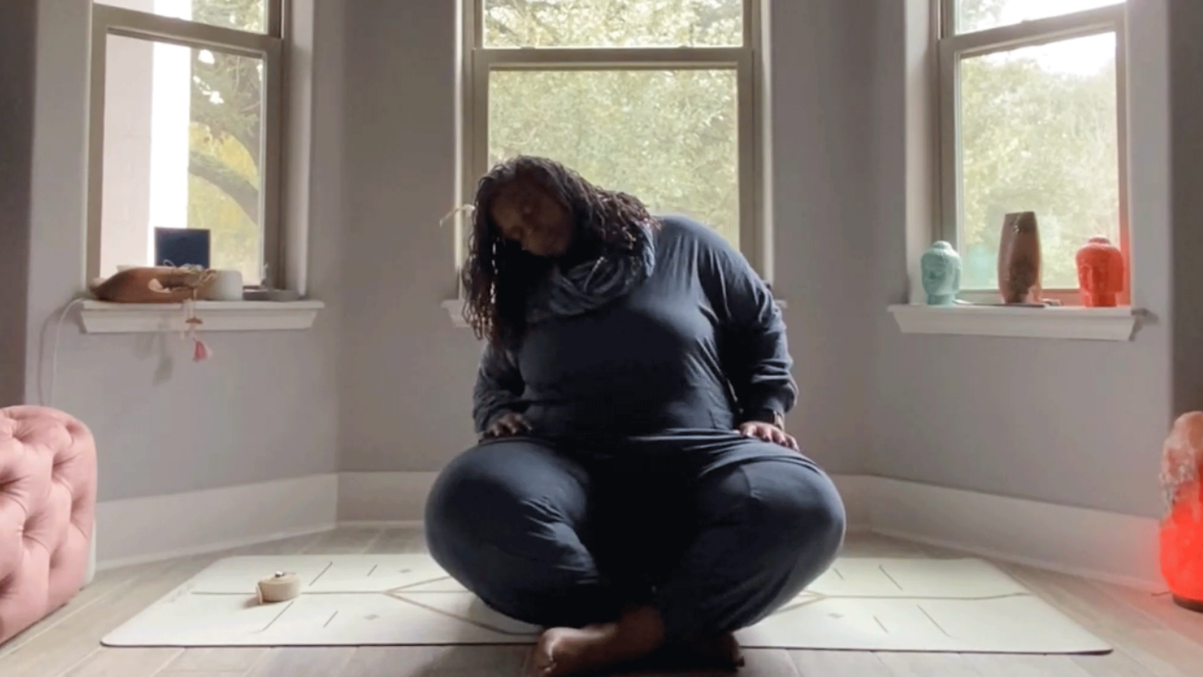 Woman doing seated neck and shoulder rolls in her bedroom