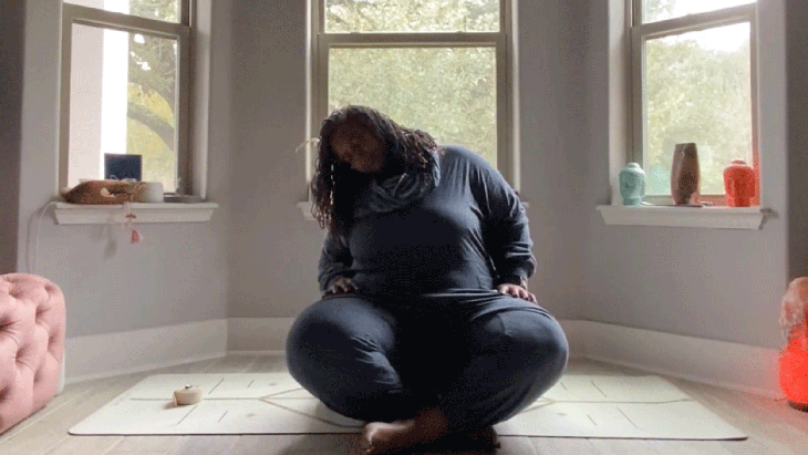 Woman doing seated neck and shoulder rolls in her bedroom