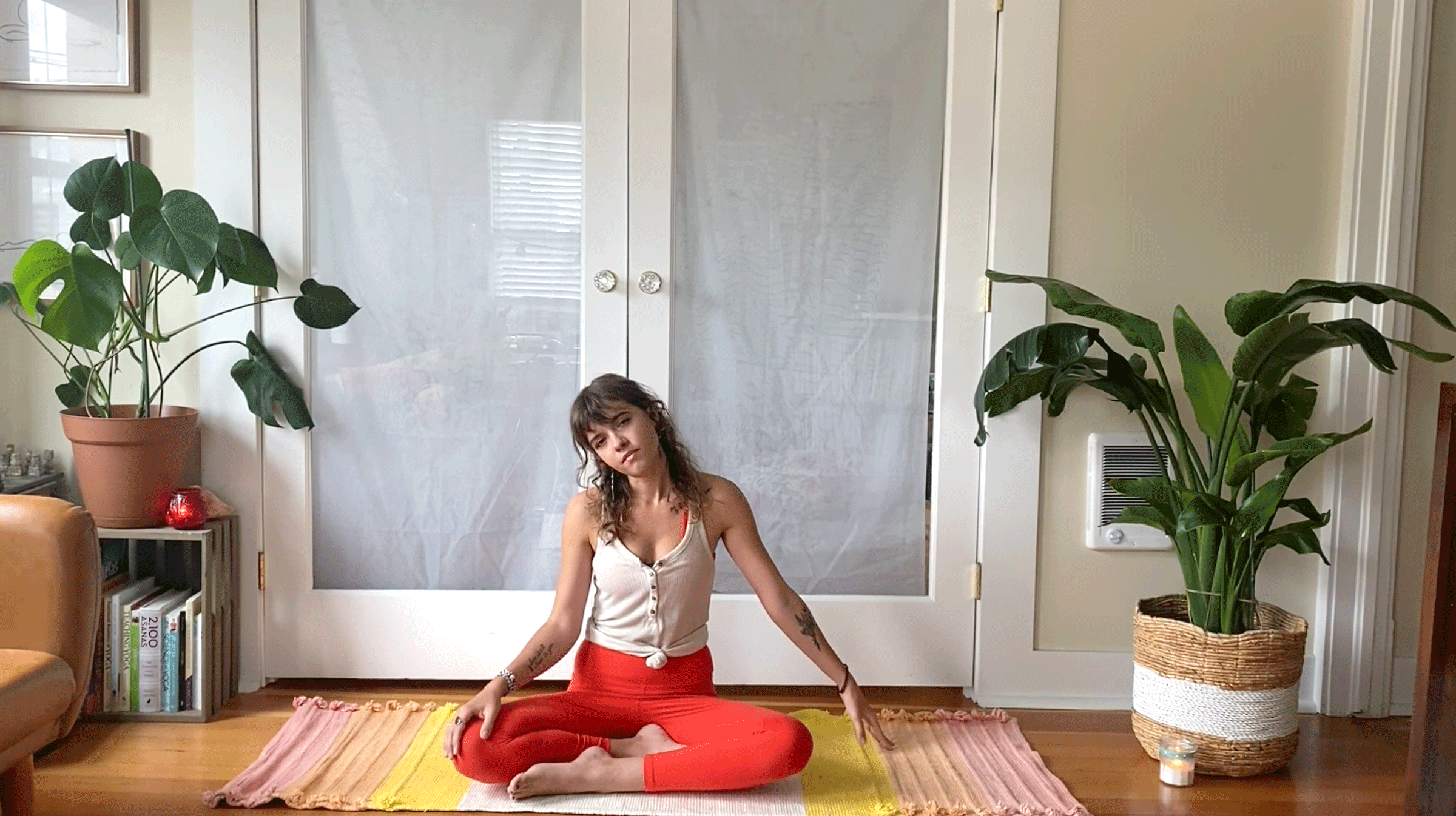 Woman seated on a yoga mat cross-legged stretching her neck to the side