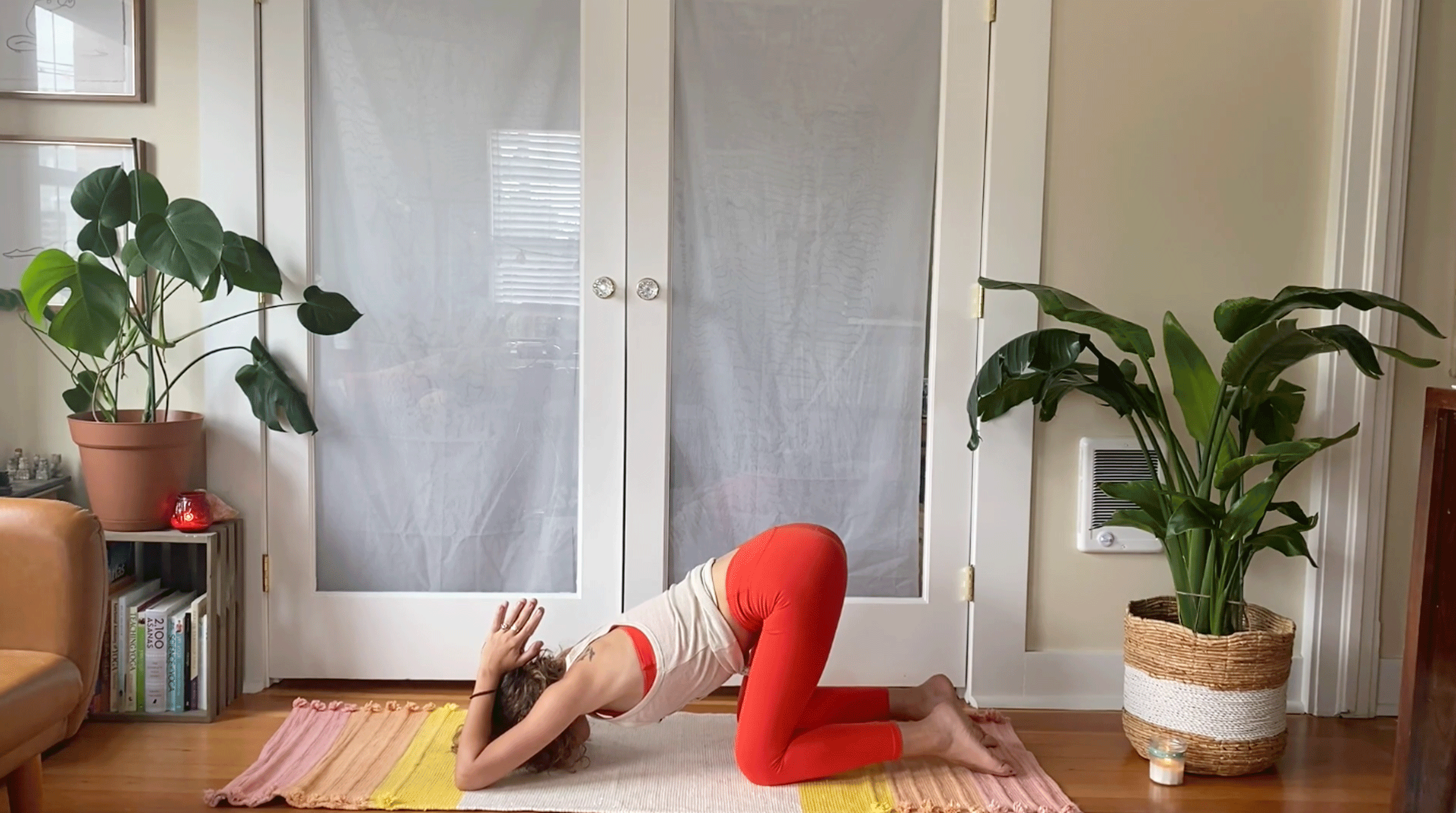Woman kneeling on her yoga mat with her elbows on the mat and her hands together in prayer behind her head.